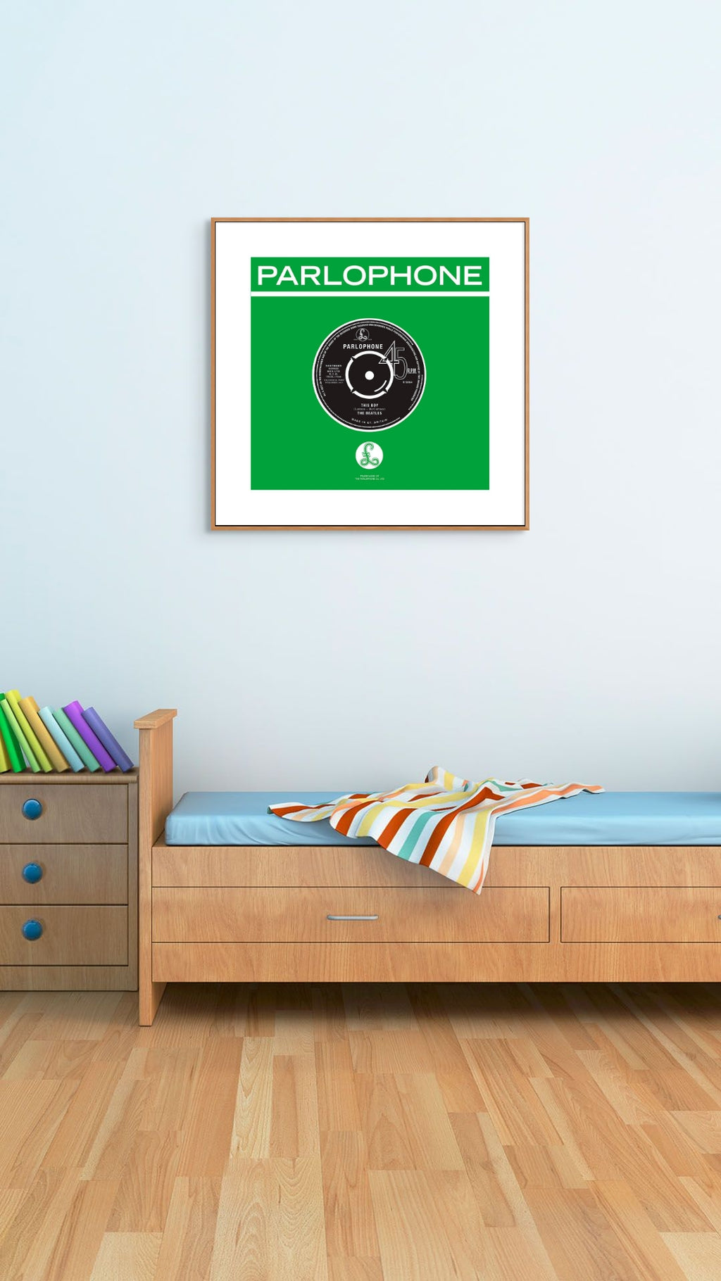 Framed Parlophone record cover on a wall above a bed with colorful bedding.